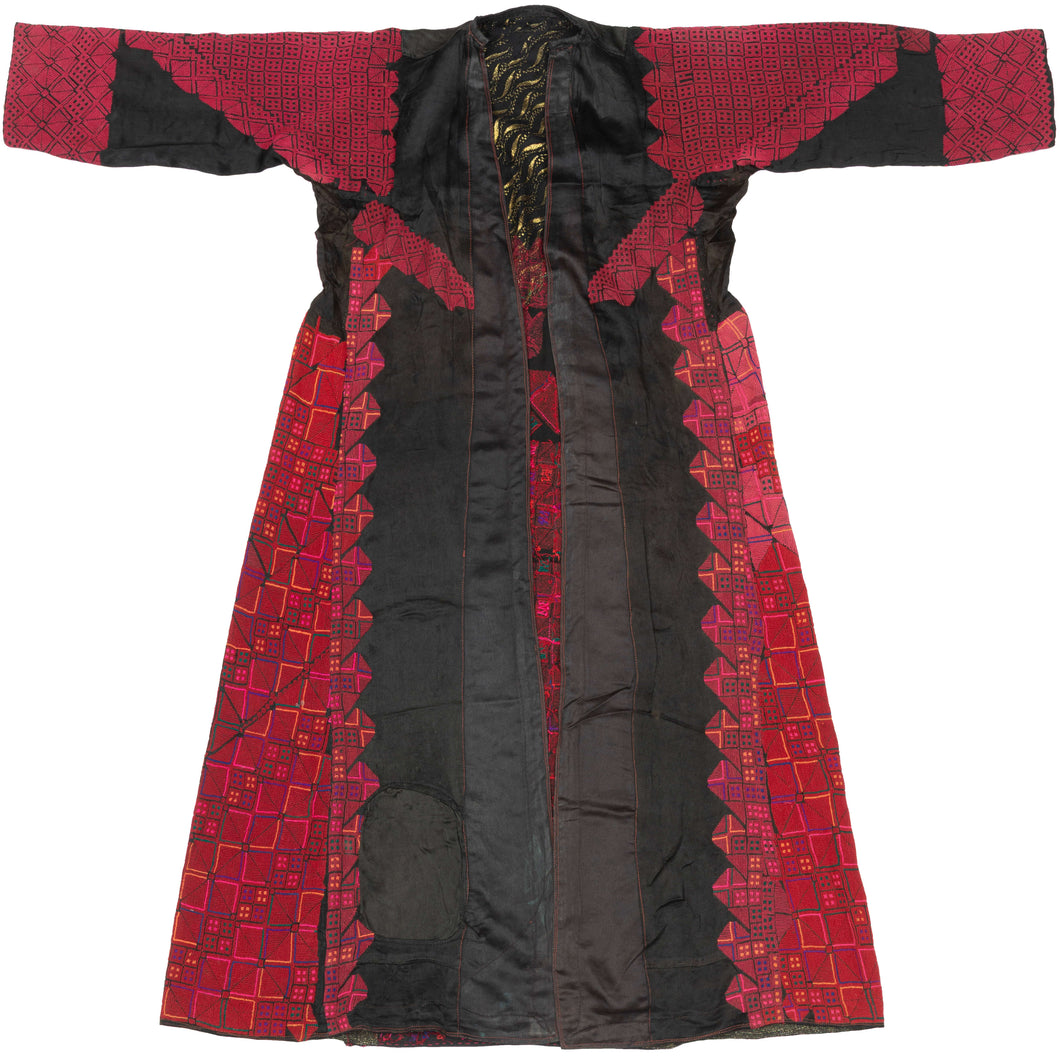 A commanding Palestinian thobe from the Ramallah–al-Bireh region of the Central Highlands, distinguished by its saturated red embroidery, dense surface coverage, and highly structured geometric composition set against a dark ground.

The embroidery is executed entirely in cross-stitch, forming tightly organized grids of stepped squares, lozenges, and subdivided diamonds across the skirt, sleeves, and shoulders. A deep triangular yoke anchors the chest, beneath which three square motifs are arranged horizont