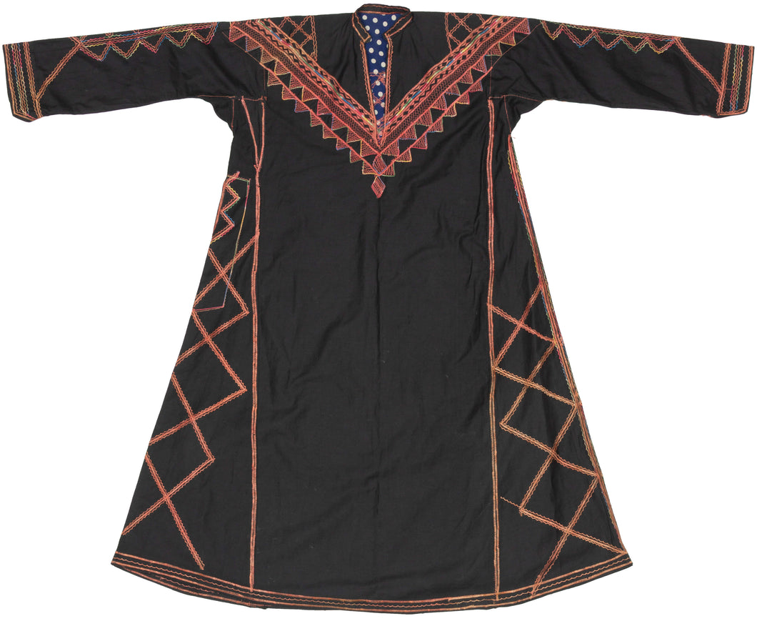A restrained and graphic Palestinian thobe from the Beersheba and Negev Bedouin region, distinguished by its dark ground, linear embroidery, and emphasis on structure rather than surface density.

Embroidery is sparingly but decisively applied, focusing on the chest, sleeves, side panels, and hem. Angular zigzags, stepped triangles, and linear motifs are arranged in bold vertical registers, while the chest features a sharply defined V-shaped yoke edged with serrated borders. Decorative stitching along seams