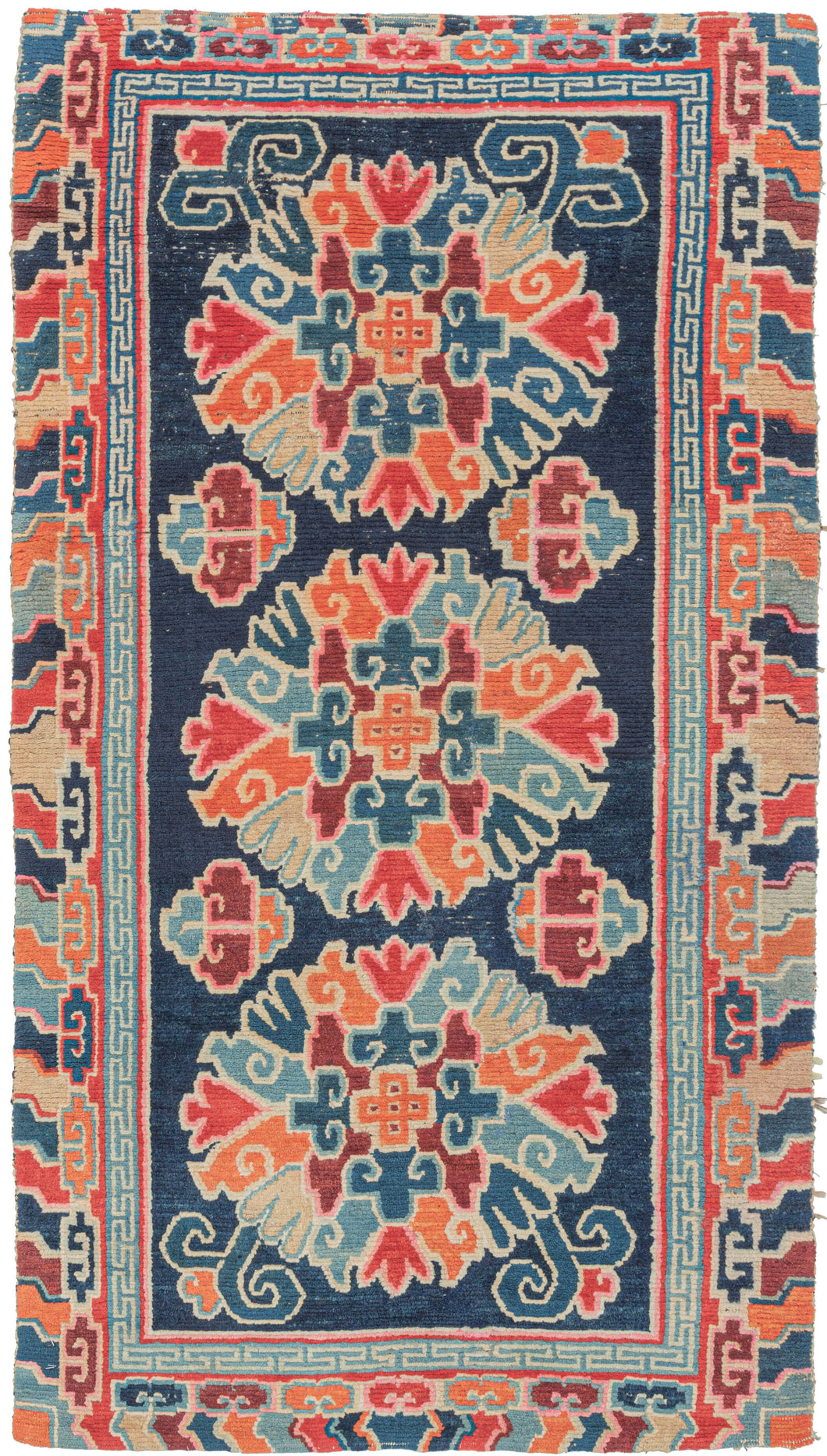 This Khaden was handwoven in Tibet during the early 20th century.   It features a three large lotus palmettes in vibrant tones of blues, reds, orange, pink and yellow and ivory on deep navy ground. With an inner minor border composed of a greek key motif and an exterior major border of energetic cloudbands. The format and design suggest use as a 