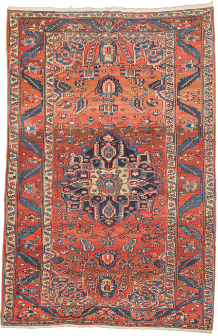 vintage bakhtiari. It features a navy central medallion on patinated red ground. The main border is in the same red and filled with serpentine leaves that swirl like bent ribbons. The blues and reds showcase a spectacular abrash or natural dye variation that give this piece fantastic movement.