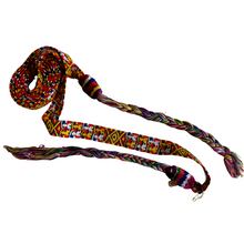 A vibrant woven cinta from Zunil, Quetzaltenango, Guatemala. This long headdress band is brocaded with repeating multicolored motifs, including geometric diamonds and stylized human figures in bright yellow, green, red, and white against a richly patterned ground. The ends finish in twisted multicolored tassels, typical of Zunil weaving.

Cintas are among the most distinctive elements of Maya women’s attire. They are wrapped elaborately around the head, creating a striking crown-like headdress, as seen in t