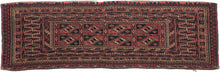 This Torba was handwoven by Tekke Turkmen Turkmenistan during the early 20th Century.  This trapping features a design of eight aina güls in earthy red, browns ivory and navy. Framed by a multitude of borders that include zigzags, flowers, diamonds and serrated leaves. A torba is a small storage used to both transport and store belongings that is similar to a chuval but not as deep. Polychrome knotheads remain of what were once long fringes.