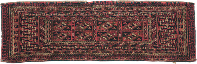 This Torba was handwoven by Tekke Turkmen Turkmenistan during the early 20th Century.  This trapping features a design of eight aina güls in earthy red, browns ivory and navy. Framed by a multitude of borders that include zigzags, flowers, diamonds and serrated leaves. A torba is a small storage used to both transport and store belongings that is similar to a chuval but not as deep. Polychrome knotheads remain of what were once long fringes.