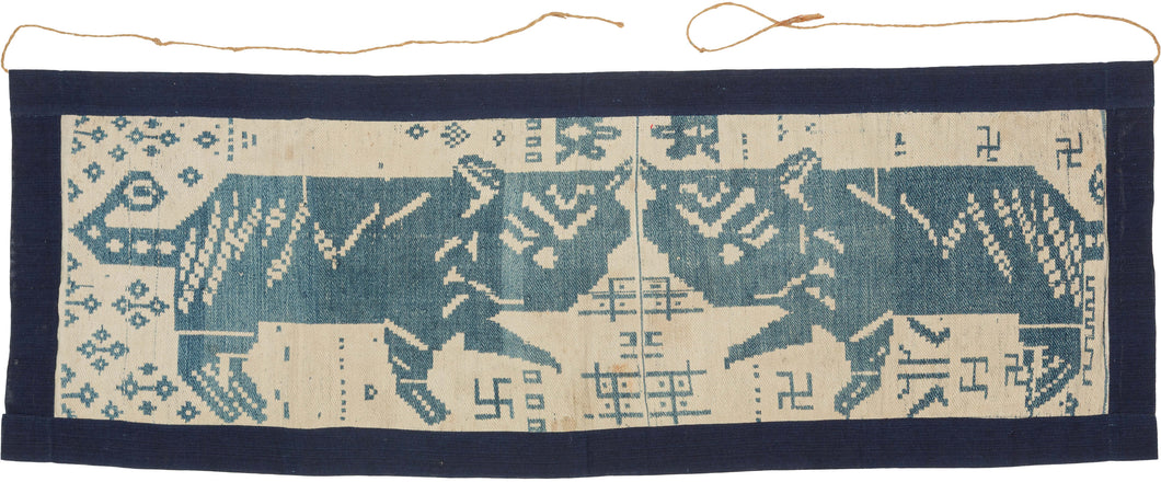 A striking central panel from a ceremonial blanket woven by the Thái ethnic community of Nghệ An, in the highlands of central Vietnam. Worked in a restrained palette of indigo blue and natural white cotton, the textile combines powerful animal imagery with auspicious geometric motifs, creating a composition that is both graphic and deeply symbolic.

The panel is organized around a mirrored pair of confronting tigers, their bodies rendered in bold, angular forms across the center of the composition. Above th