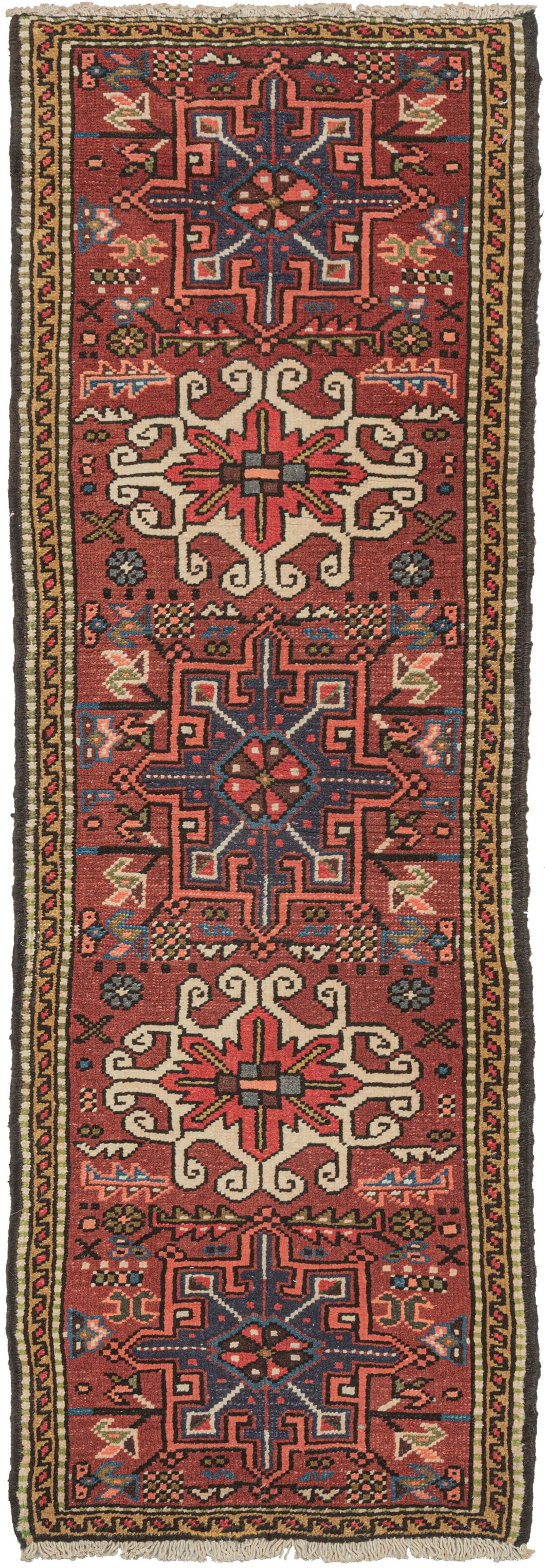 Vintage small Karaja runner featuring a pattern of alternating geometric shapes and hooked lozenges on a brownish-red ground. The ivory-hooked lozenges have a little more of an extra curl here giving it some distinct personality. Blues, purple, charcoal, gold, pink, and ivory complete the palette. In a rare narrow and short runner format.