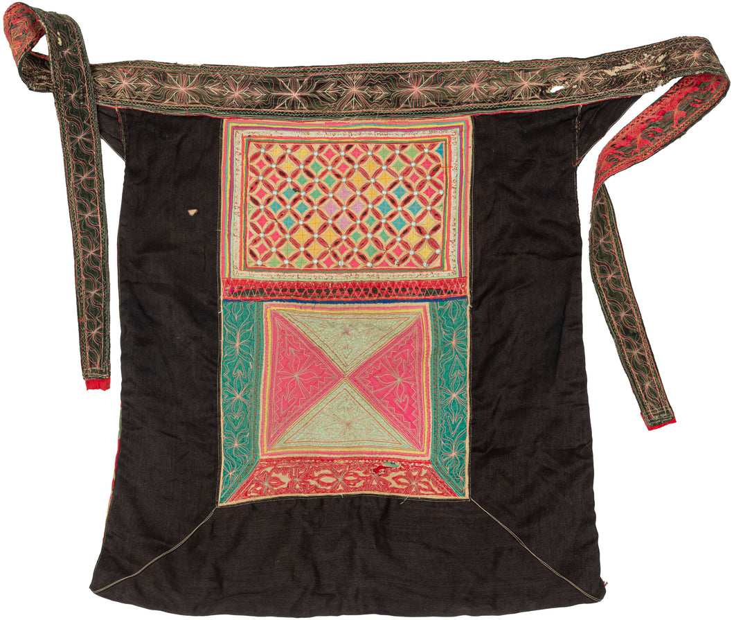 A richly decorated baby carrier from the Xa Phang people, dating to the mid 20th century. Made from dark cotton cloth, it is embellished with vivid embroidery, appliqué, pieced textile panels, and rows of small metal studs that catch the light across the central panel.

Among the Xa Phang, baby carriers are both practical and deeply personal objects. They allow a mother to keep her child close throughout daily life while also serving as a highly visible expression of textile skill, care, and cultural identi