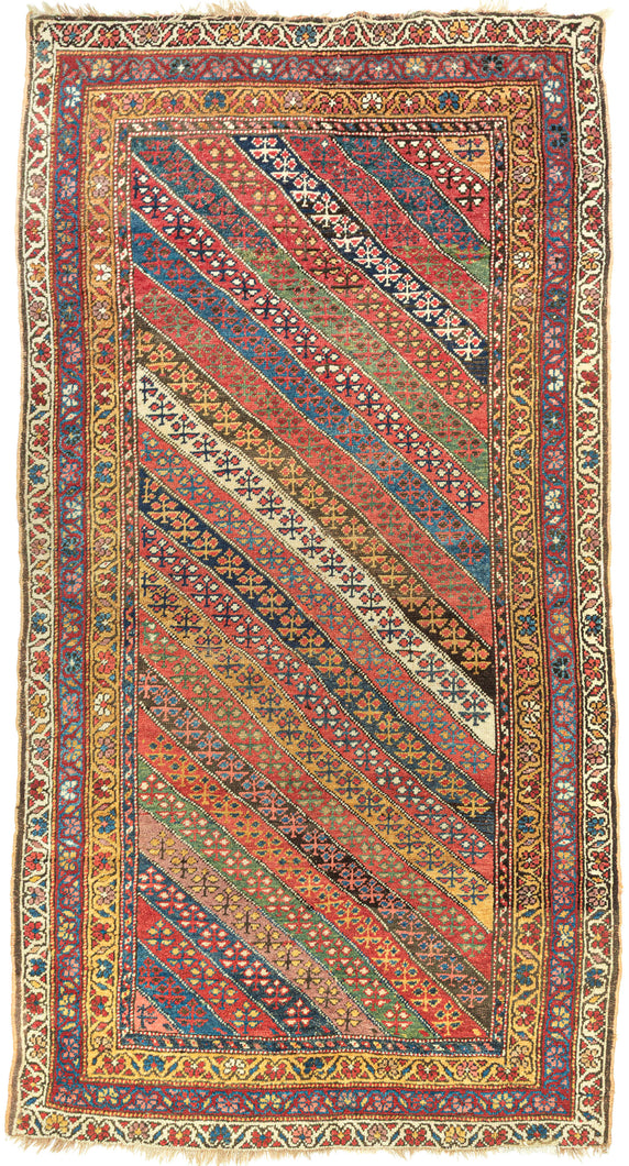 An exceptional Kurdish rug distinguished above all by its top-notch color and superb wool. The field is composed of lively diagonal bands, each carrying a different floral or geometric repeat and shifting through saturated brick red, deep indigo, grassy green, ivory, ochre, aubergine, and soft rose.
