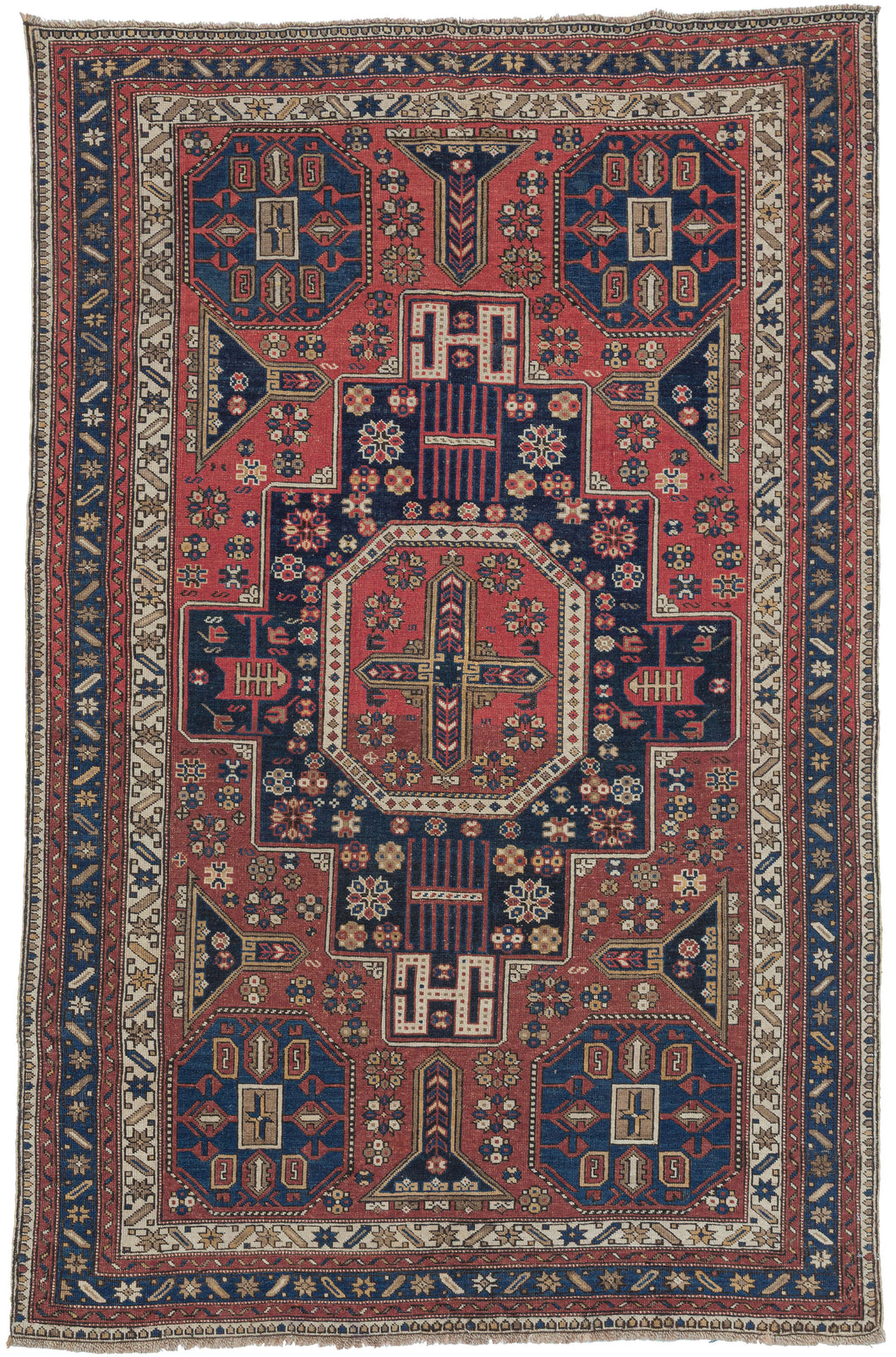 A superb late-19th-century Shirvan whose design vocabulary is more commonly encountered in Shirvan and Kuba Soumaks. The octagonal medallion-and-panel layout, the dense scattering of small rosettes, and the talismanic latch-hook devices all echo the structural geometry of flatwoven Soumak covers which is here translated into a finely knotted pile format with striking clarity. This crossover of motifs is both unusual and highly collectible, reflecting the deep interchange between pile-weaving and flatweave t