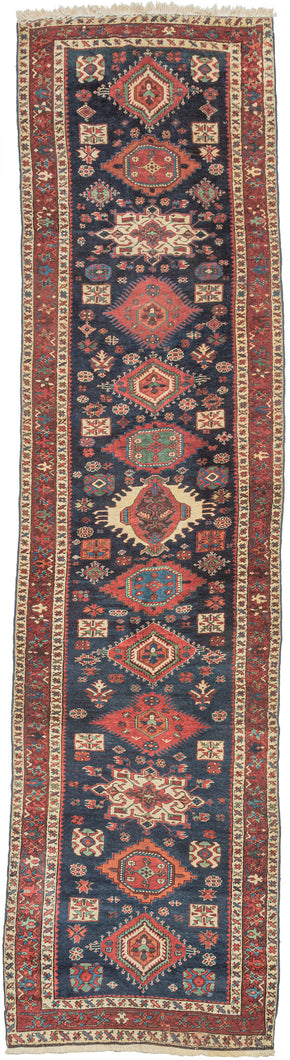 Karadagh It features a series of nested medallions that march down a rich abrashed indigo field. The medallions are rendered in blues, green, red, apricot and aubergine with geometric symbols and figures filling out the negative space. The pile is low and of lush high quality wool.