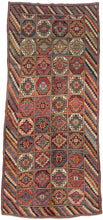 A boldly patterned antique Kurdish long rug woven with a striking compartment design. The field is organized into a grid of stepped, octagonal Memling guls, each enclosing a central rosette, rendered in a rich palette of madder red, indigo blue, ivory, soft camel, brown, and green.

The Memling gul, an ancient geometric motif appearing across many Caucasian and Kurdish weaving traditions, gives the rug its powerful visual structure. Here, the repeated guls are framed by an especially lively diagonal-striped