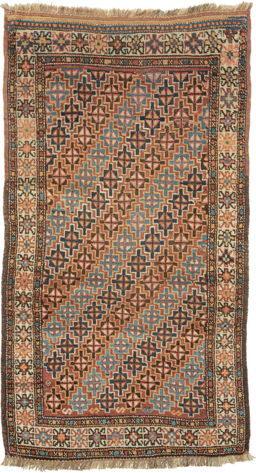 An antique Quchan Kurdish rug woven with an allover field of small stepped geometric medallions in soft salmon, indigo blue, turquoise, ivory, and warm brown. The closely arranged motifs create a lively, mosaic-like surface, framed by an ivory floral border and narrow geometric guard borders.

Quchan rugs were woven by Kurdish communities in the Khorasan region and are admired for their strong tribal drawing, durable construction, and expressive use of color. This example is especially appealing for its com