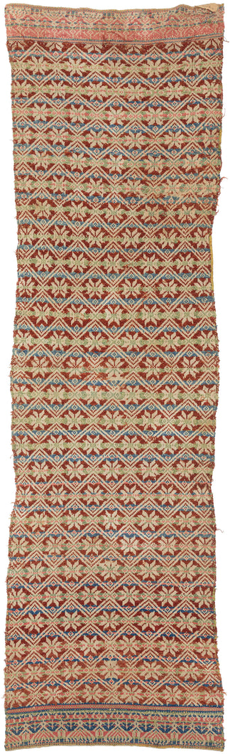 This elongated brocaded panel reflects the celebrated weaving traditions of Samugheo, the Sardinian village renowned for its mastery of pibiones “grain” weave and richly patterned household textiles. The central field displays repeated diamonds enclosing stylized stars, while the end skirts feature rare anthropomorphic figures that read either as a man and woman in union or dancers repeated in procession-like rhythm. Their presence evokes fertility, marriage, and communal celebration, suggesting the textile