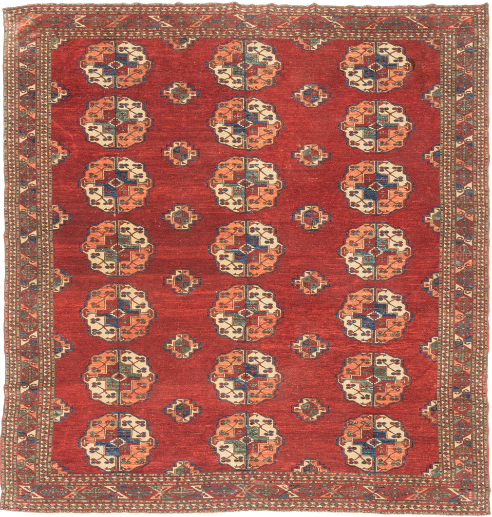 This Tekke main rug was handwoven during the first quarter of the 20th century in Turkmenistan.

The field features a grid rounded main guls in apricot, indigo, turquoise and ivory on vibrant red ground. The space between the grid is filled with rows of cruciform shaped secondary guls. In a rare square format that allows for very luxurious and open spacing of the guls.