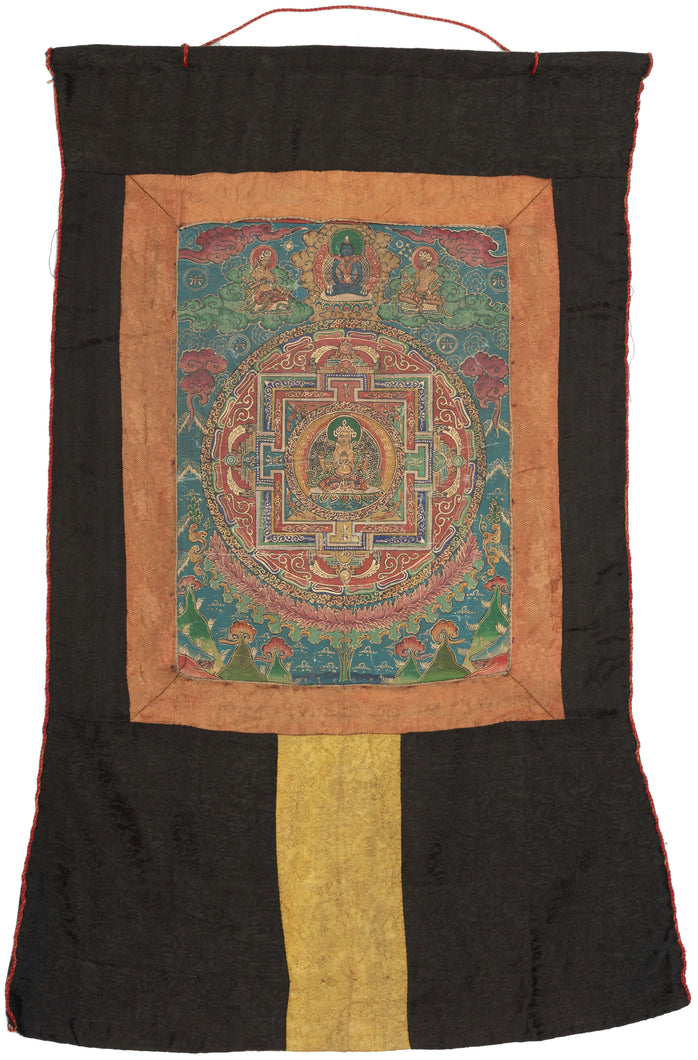 This exquisite thangka presents a meticulously detailed mandala centered on Vairocana Buddha, the cosmic embodiment of wisdom and illumination. Seated in serene meditation on a lotus throne, Vairocana is encircled by layers of symbolic architecture, gates, lotus petals, and flame motifs which represent the sacred geometry of enlightenment and the path toward spiritual realization.