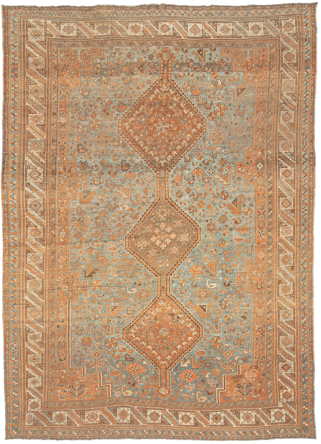 This washed Shiraz rug features a series of stacked diamond medallions running the length of the field, connected by angular stems and surrounded by a dense scattering of small protective symbols and geometric motifs. The design is assertive yet approachable, with a clear sense of structure.
