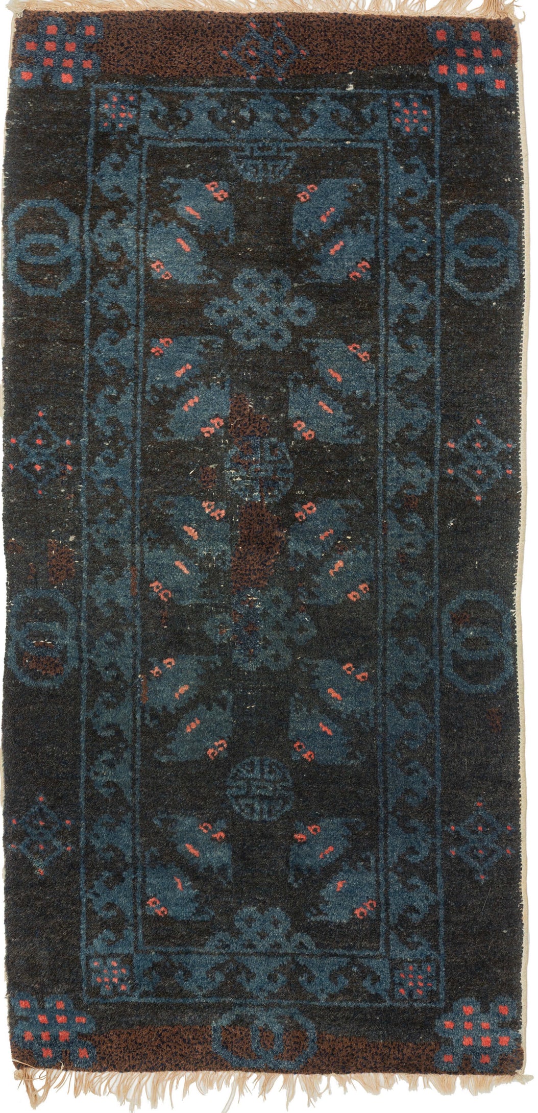 A small Gansu rug woven with a lively arrangement of auspicious symbols against a deep navy field, accented in indigo blue, coral, and muted aubergine. Pairs of stylized bats appear throughout the central field, arranged around endless knots and&nbsp;shou symbols, while interlocking ring motifs line the outer border.

In Chinese decorative arts, the bat is a symbol of good fortune, while the shou character represents longevity and the endless knot suggests continuity and enduring harmony. 