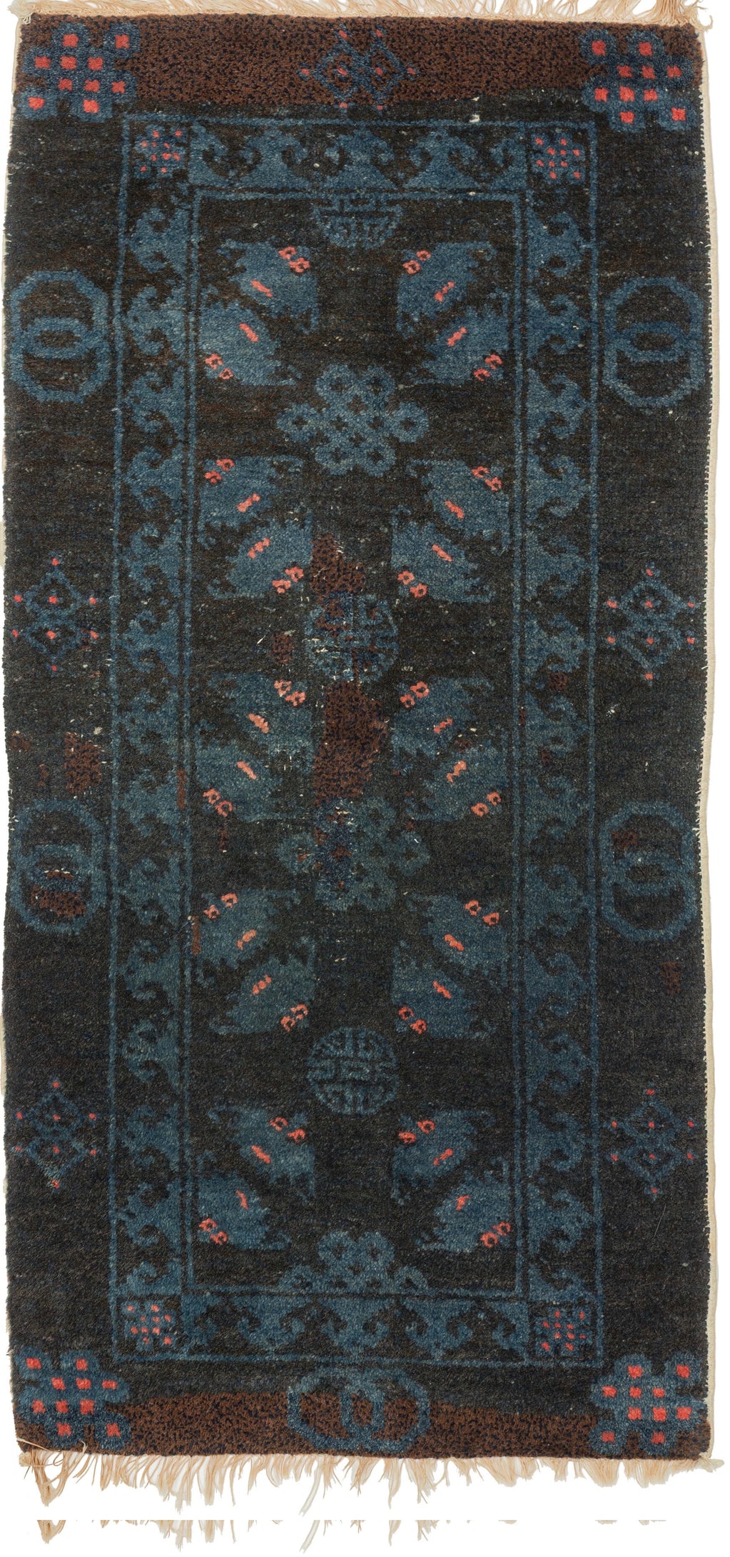 A small Gansu rug woven with a lively arrangement of auspicious symbols against a deep navy field, accented in indigo blue, coral, and muted aubergine. Pairs of stylized bats appear throughout the central field, arranged around endless knots and&nbsp;shou symbols, while interlocking ring motifs line the outer border.

In Chinese decorative arts, the bat is a symbol of good fortune, while the shou character represents longevity and the endless knot suggests continuity and enduring harmony. Together