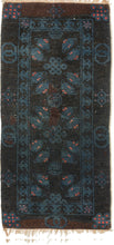 A small Gansu rug woven with a lively arrangement of auspicious symbols against a deep navy field, accented in indigo blue, coral, and muted aubergine. Pairs of stylized bats appear throughout the central field, arranged around endless knots and&nbsp;shou symbols, while interlocking ring motifs line the outer border.

In Chinese decorative arts, the bat is a symbol of good fortune, while the shou character represents longevity and the endless knot suggests continuity and enduring harmony. Together
