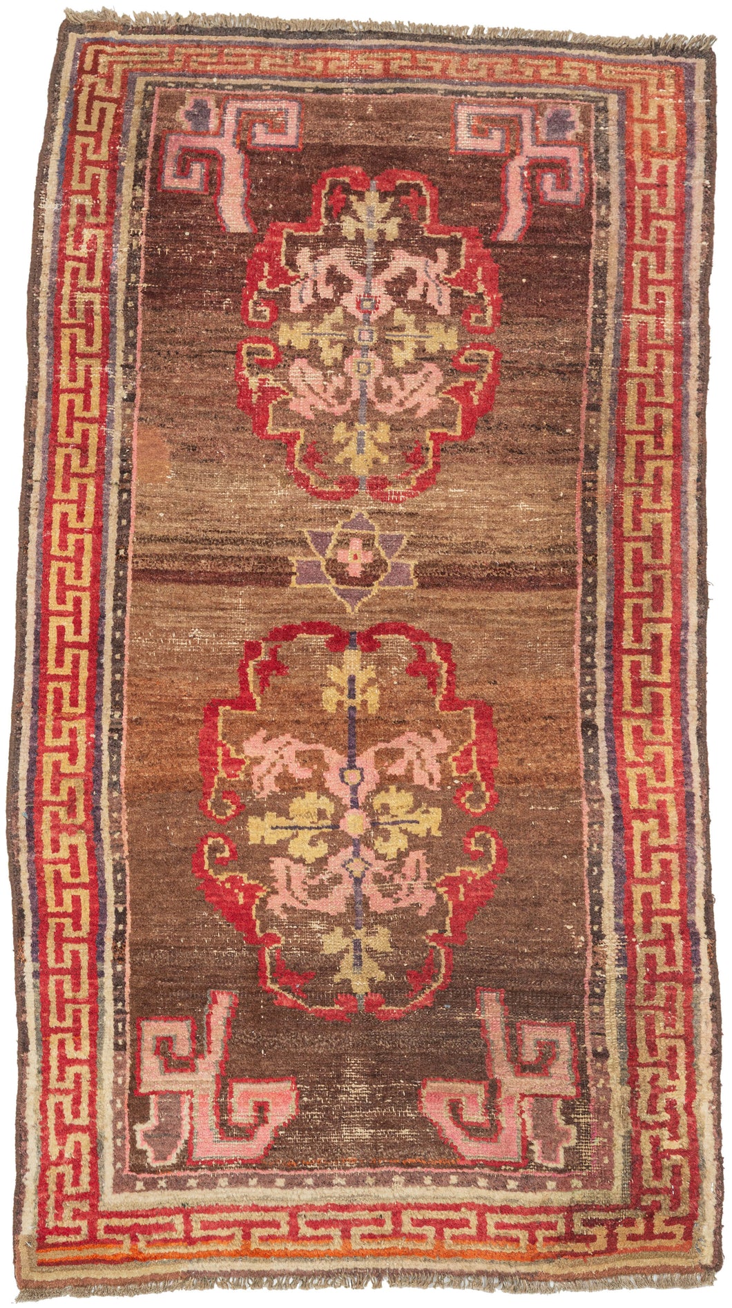 A character-rich Tibetan rug with a warm brown field and bold medallion motifs framed by a striking red key border. The saturated reds and soft pinks contrast beautifully against the earthy ground, while subtle abrash and wear create depth and texture across the surface.