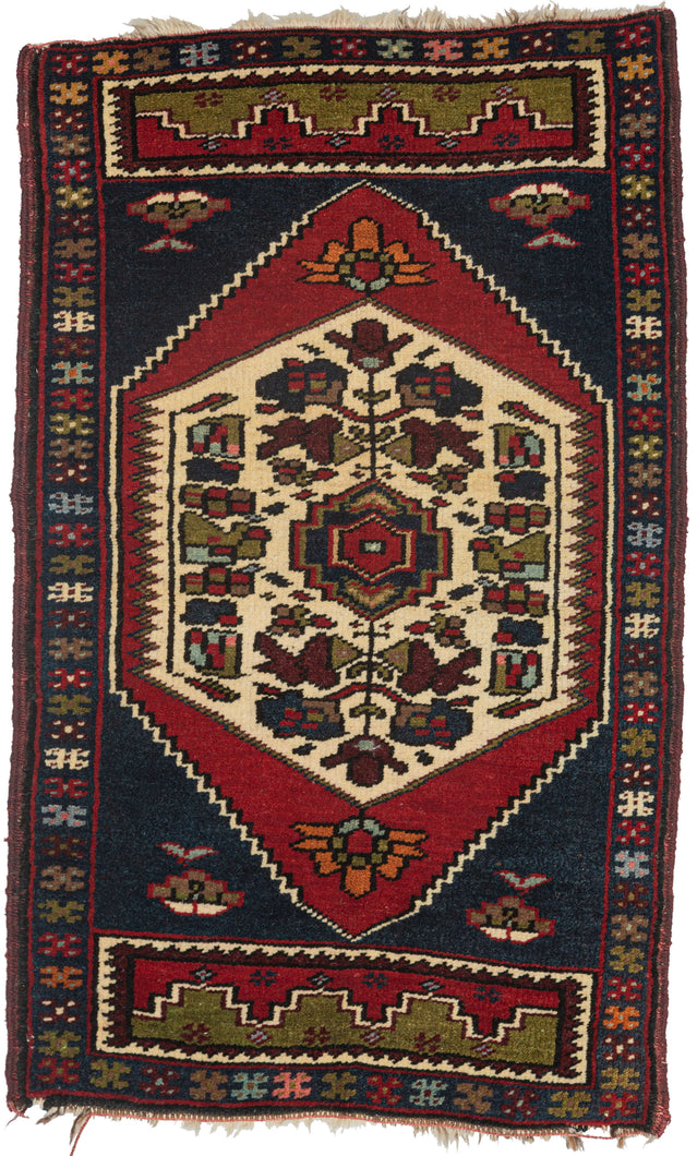 This Yastik was handwoven in Turkey at the end of the 20th century. It features a strong, funky palette of tomato red, sour green, and deep blue, with shots of burgundy and ivory for contrast. The central medallion is framed by an X border resembling rainbow stars.