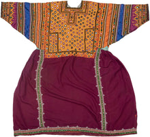 This striking vintage dress from Sindh, Pakistan, showcases the region’s renowned textile artistry through dazzling mirrorwork embroidery (shisha) on a richly dyed base. The bodice and sleeves are densely adorned with geometric mirror insets, chain-stitch embroidery, and floral motifs, worked in bold jewel tones on ochre, orange, and cobalt panels. The lower portion of the dress is a deep maroon cotton, finely detailed with vertical bands of white bead-like embroidery and green piping, adding balance and el