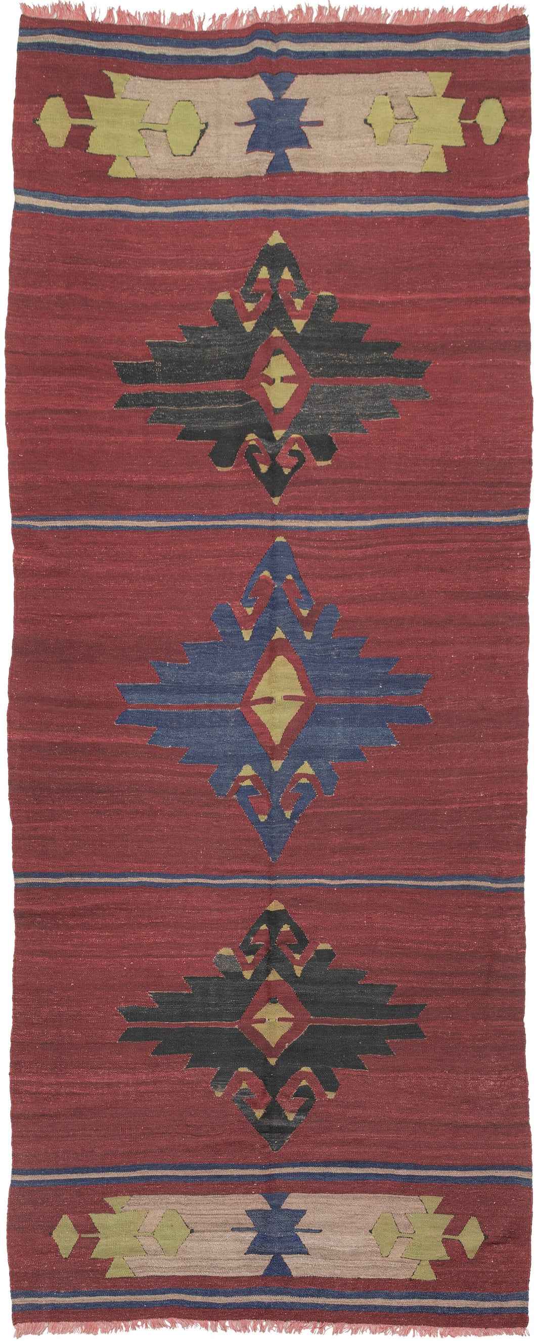 Anatolian kilim that features a simple yet striking composition. The kilim is borderless and broken into five horizontal sections separated by thin blue and tan stripes on a dramatic dark raspberry field. The top and bottom sections are composed of matching cartouche like devices in chartruese, tan and periwinkle. The inner panels feature three graphic hooked medallions; the central periwinkle medallion flanked by two darker black medallions.