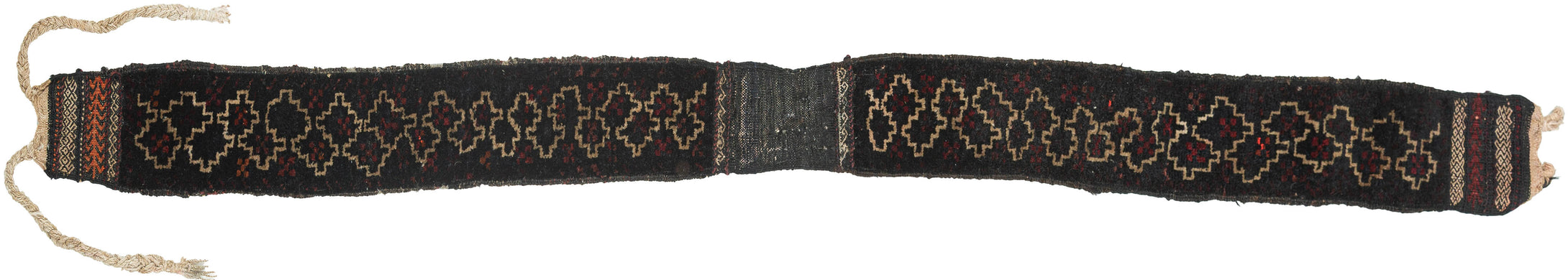 A striking Baluch animal trapping, woven in a long, narrow format with its original braided ties still attached. The design is spare and powerful with a dark wool ground animated by a chain of ivory stepped motifs, small flashes of madder red, and compact end panels with orange and ivory geometric borders.