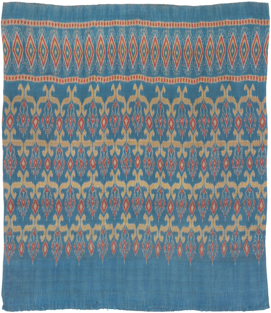 This elegant silk pha sin or traditional tube skirt was handmade in northeast Thailand during the middle of the 20th century.

It is a masterful example of mudmee (ikat) weaving from the Isaan region. The main field (phuen sinh) showcases a staggered arrangement of stylized vegetal or flame motifs in golden ochre and brick red, which is an elegant reinterpretation of classic Lao-Tai design language passed down through generations of Isaan weavers.

The upper band (hua sinh) is particularly dynamic with a ro