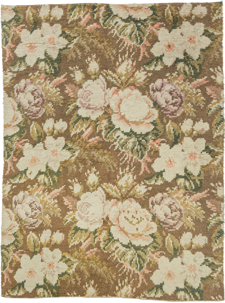 A richly textured Scandinavian rya rug with a loose, hand-knotted pile forming a lush field of oversized floral motifs. Large blossoms and leafy forms unfold across a warm brown ground in soft shades of ivory, blush pink, sage green, and muted gold, creating a painterly, almost tapestry-like composition.