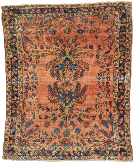 This cheerful Lilihan is distinguished by an especially striking mirrored bouquet motif, in which scrolling vines grow from two central bouquets, each adorned with large, hanging serrated leaves. Set against a warm coral field, the design feels both formal and expressive, with the unusual mirrored botanical elements radiating outward in a balanced, confident arrangement.