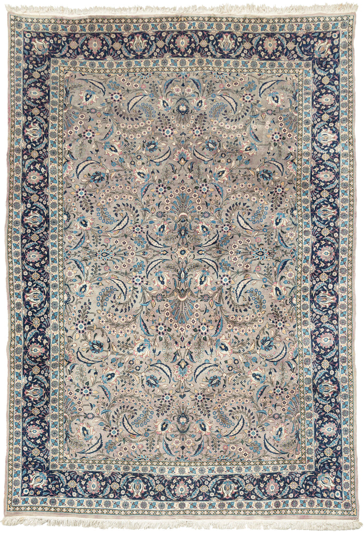 This Mashad rug was handwoven during the middle of the 20th century.

It features an allover design that radiates from a central axis with mirrored sprays of stylized palmettes, saz leaves and rosettes in shades of icy blue, indigo, shell pink and ivory on a silver ground. Nicely framed by a perfectly reconciled main border of palmettes on a midnight blue ground. The original ground color was a purple tone that was not color fast and has perfectly faded into a cool silver tone which is very uncommon in vint
