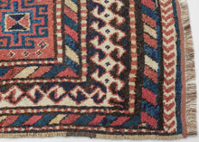 QUCHAN KURD It features a central "Hawzi" motif with three memling guls on the top and the bottom in primary colors of red, yellow and blue with ivory and brown accents on a brick red ground . The "Hawzi" or water tank design is architecturally inspired and references the water reservoirs found in gardens, mosques and village squares. Framed by a series of interesting borders including a main border that shifts from rams heads along the sides to both single running dog and double running dog motifs 