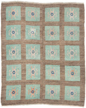 A wonderfully graphic vintage latch-hook rug with a repeating grid of aqua panels, each centered by a playful abstract motif in soft blush, salmon, and deep blue. The warm brown ground gives the composition structure while allowing the almost cellular, biomorphic forms to float across the surface.