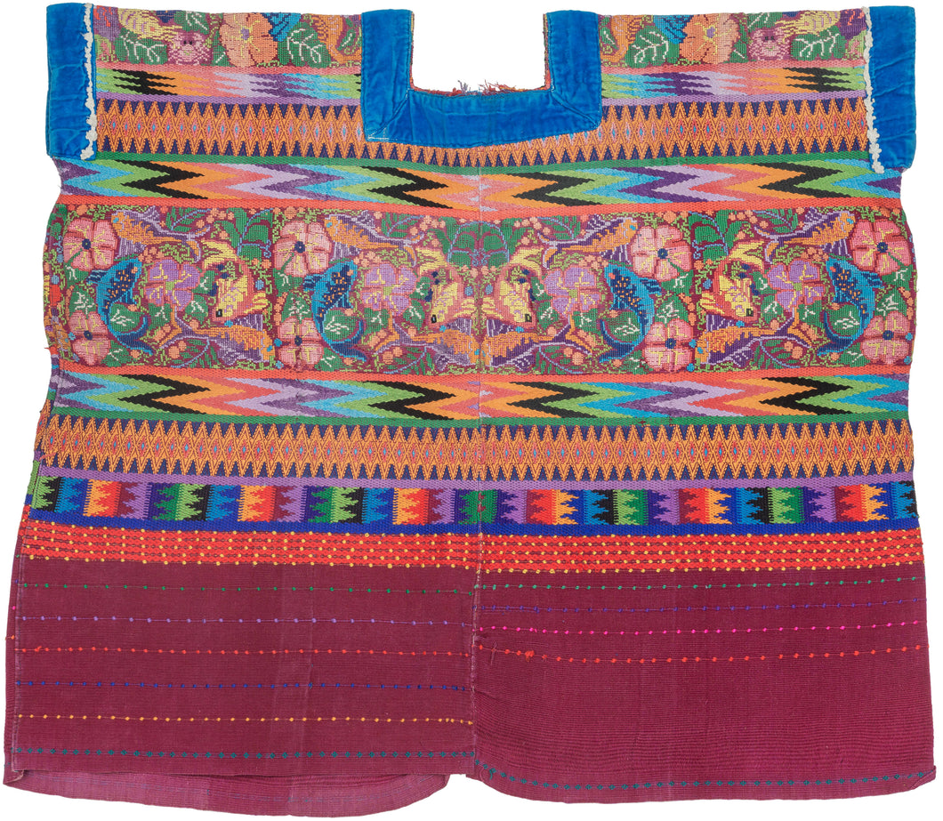 This spectacular Huipil is alive with symbolism and saturated color. The brocaded upper panel features a lush tableau of birds, flowers, and brilliantly woven fish, each motif carrying deep resonance in Maya tradition. Birds evoke freedom and the sky, flowers embody fertility and beauty, and fish symbolize life’s connection to water and abundance.

