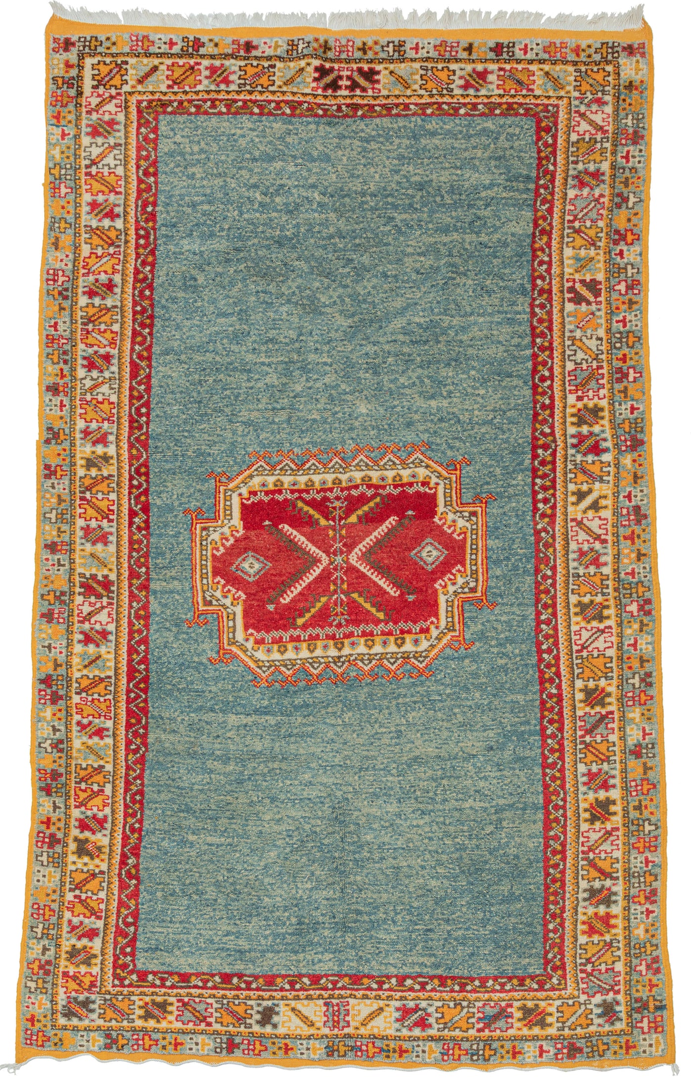 Handwoven by Amazigh weavers of the Aït Ouaouzguite tribe in Morocco’s High Atlas Mountains, this vintage rug reflects one of the region’s most celebrated weaving traditions. Distinguished by its fine weave, bold geometric design, and brilliant saffron yellow, a hallmark of Aït Ouaouzguite textiles, it embodies the vibrant artistry that has made these rugs among Morocco’s most sought-after weavings. The motifs are set against expansive fields of luminous ocean blue, whose generous negative space lends the c