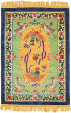 This silk rug was handwoven during the 3rd quarter of the 20th century in Tianjin, China.It features a central scene of two mythological fenghuangs surrounding a red and pink peony on a yellow ground. The yellow oval is flanked by four prancing stags on a seafoam green ground. The whole is framed by a border of blossoming red and pink peonies on green vines and finished a thick block of navy around the perimeter.