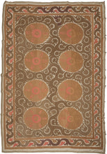 A large Central Asian suzani embroidered with eight circular medallions set within a flowing field of scrolling vines. The warm earth-toned ground is animated by soft coral and rose accents, while the surrounding ivory negative space gives the design clarity and movement.