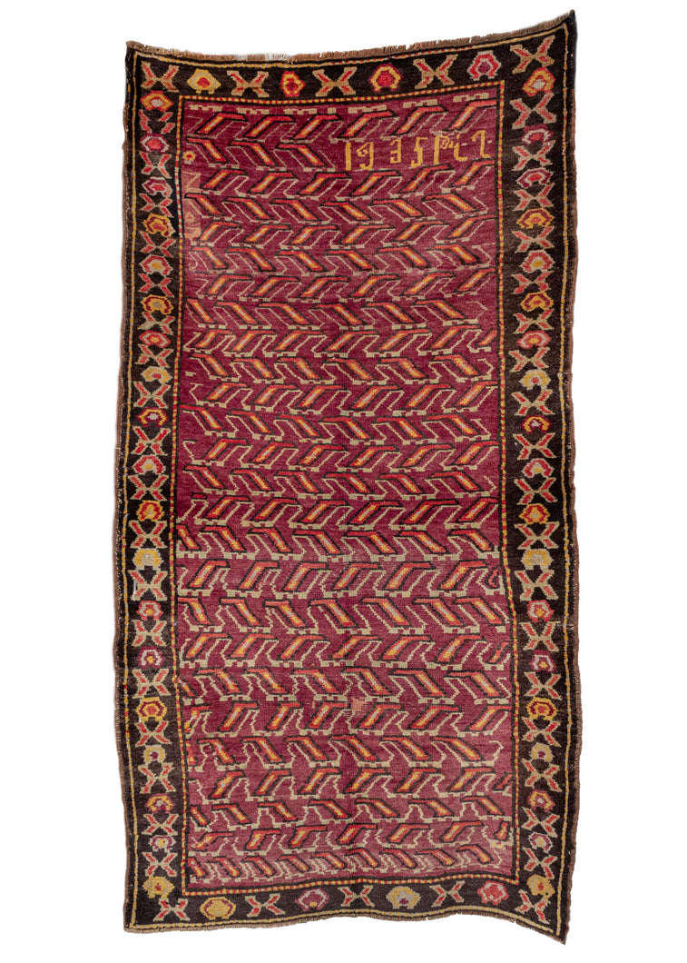 Armenian rug handwoven in 1935. Uncommon geometric composition in yellow and red on a rare purple field. Border has abstract geometric shapes on a dark brown field. 