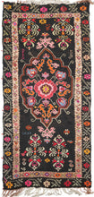 dated 1963 anatolian kelleghi kilim featuring energetic tones of hot pink, bright orange, purple, blue, yellow green, and red that really pop against the black ground. Of particular interest are the inclusions of the names "Cicek", "Semiye", "Ummiye" and the date "1963" woven into the field. It is likely this kilim was woven for domestic use and not for sale. The long fringes that alternate between handspun wool and braided cotton.