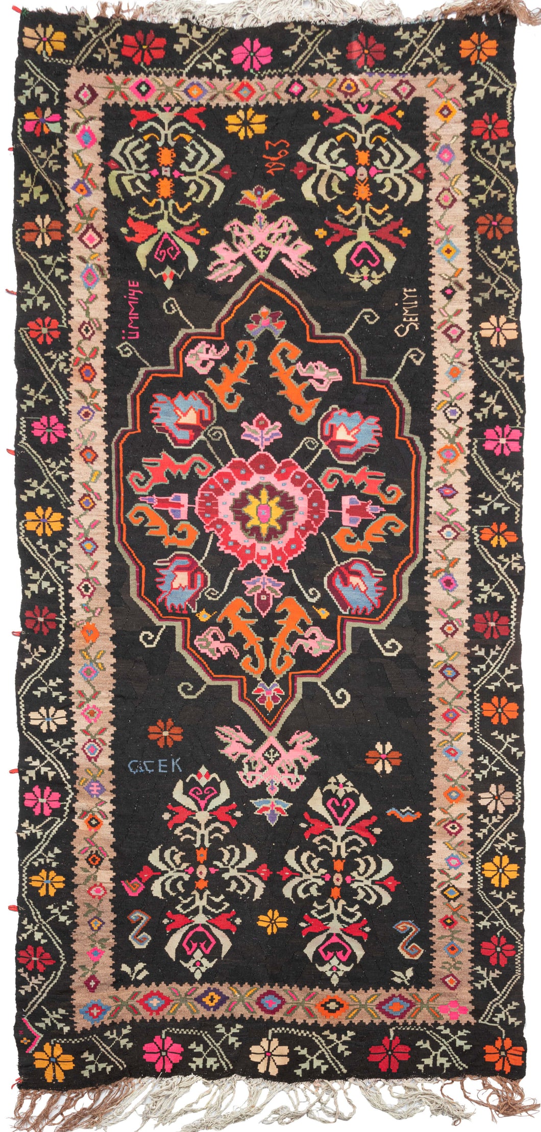 dated 1963 anatolian kelleghi kilim featuring energetic tones of hot pink, bright orange, purple, blue, yellow green, and red that really pop against the black ground. Of particular interest are the inclusions of the names 