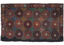 This Tus Kiiz Yurt Embroidery was embroidered in western Mongolia by ethnic Kazakhs and features the embroidered date of '1981' in the bottom right corner.  Features a pattern of densely chain stitched rosettes in reds, blues, and yellows. The right side of the embroidery is purposefully unfinished. 