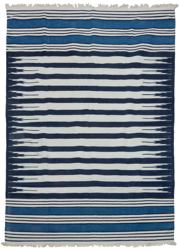 19th century Indian Jail dhurrie featuring a series rows of deep navy and bright white stripes which feather at each end in the central panel. Two skirt panels feature smaller alternating white and navy stripes broken up by two bright indigo blocks. These rugs were part of prison reform beginning in 19th century India.