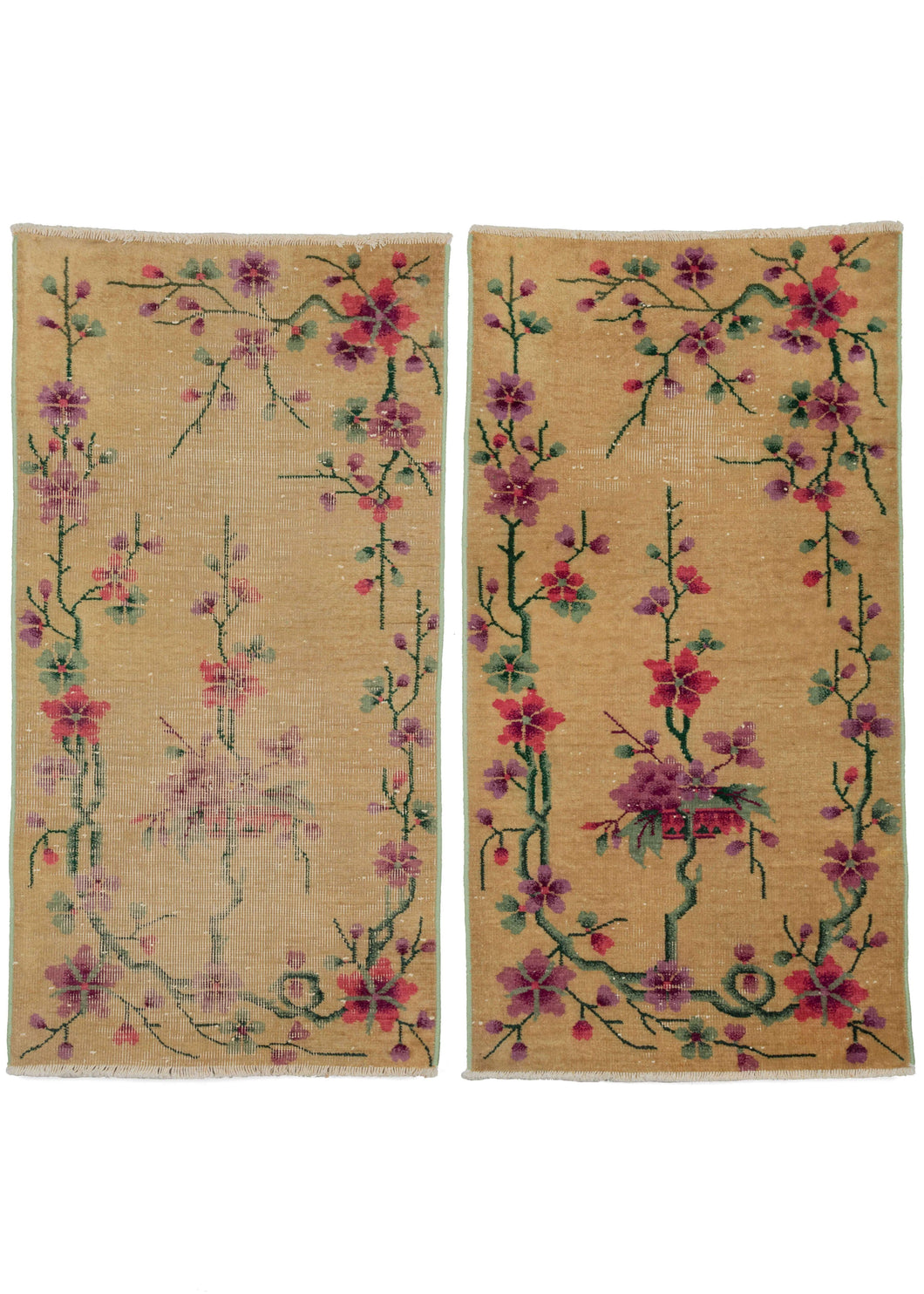 Two matching antique yellow deco scatter rugs featuring a delicate floral design in soft purples, greens, and bright pinks, all on a yellow ground. In varying conditions: one is in good condition, with one slightly worn patch while in the other a majority of the field is worn, as pictured. Both have a low pile and a very sturdy handle. Both rugs have reinforced edges and sides to increase longevity.