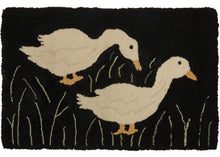 Small American craft hooked rug featuring a staggered pair of geese in tall grass, on a black field.