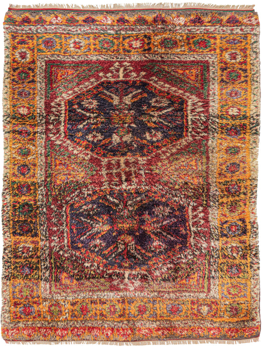 Anatolian Yatak shag area rug featuring a field of two medallions woven of thick shaggy wool. The thickness of the wool blurs the design in an interesting almost as if the whole rug was vibrating. in a well-balanced and interesting palette of reds, oranges, purple, yellow, greens, and ivories. This style of rug is common in central Anatolia and is known as a Yatak and has origins as a bedding rug.