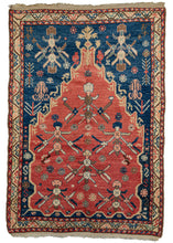 Antique Anatolian prayer rug featuring a red ground mihrab with six flowering trees or shrub-like motifs. The mihrab is surrounded by a navy ground showcasing a variety of vegetation and protection symbols including two more shrub-like motifs found in the mihrab. Atop the contrasting red and navy grounds accents have been added in pleasing tones of green pink, yellow, chocolate, and ivory. The whole is framed by flowering vine main border and two swirling ribbon minor borders. 