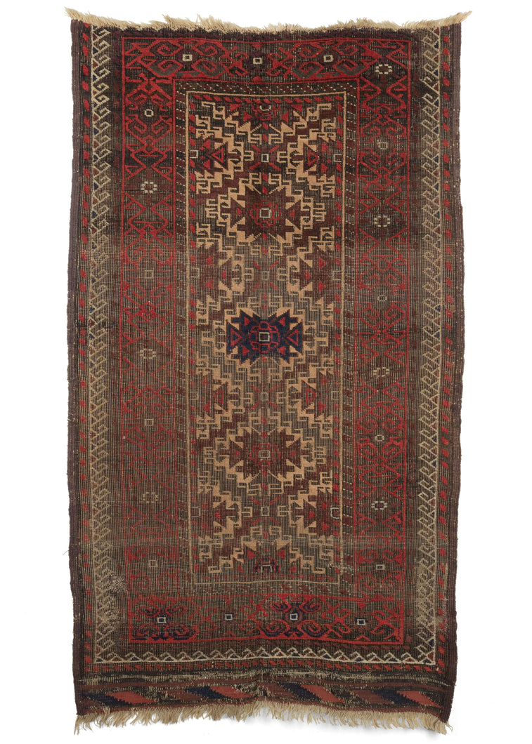 Antique Baluch scatter rug featuring madder red and aubergine dyed wool playinng nicely with soothing camel and oxidized browns, while a pop of indigo shines dead center and makes another appearance in the intact kilim edge. Both the warp and weft are constructed out of handspun wool. 