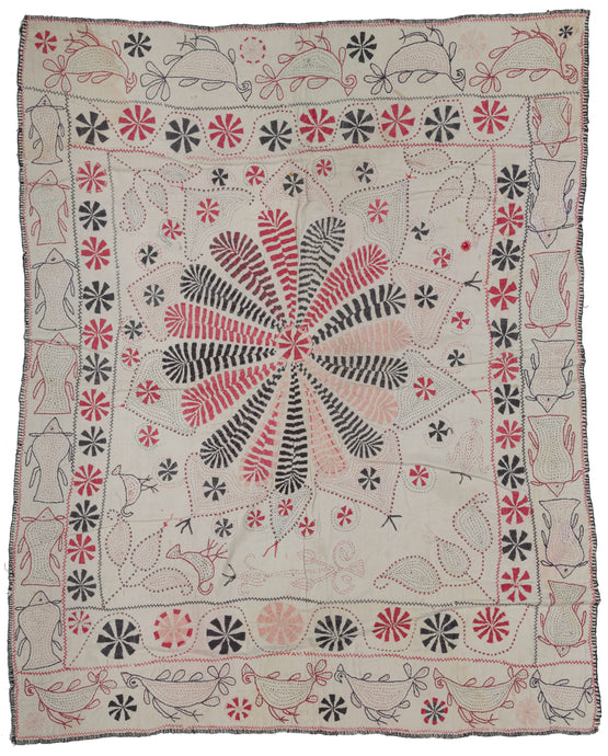 Antique Kantha featuring a central floral mandala with vegetal forms in each cornice. It has a limited palette of various red and black threads on plain white cotton ground. The red and black threads were likely harvested and reused from old clothing.  A mixed border of local fish (Ilish) on the vertical and birds (Doyel) on the horizontal frame the whole. Look closely to notice two small birds in one cornice. 