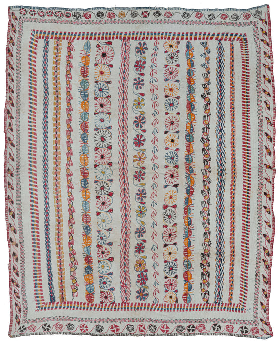 Antique Bengali Kantha featuring a field full of columns from pinwheels and floral meanders to zig zags and simple shapes. Crisply and meticulously rendered with a wide and vibrant color palette on a white cotton ground. Framed around the perimeter by mixed scroll borders of flower buds on the vertical and pinwheels on the horizontal. 