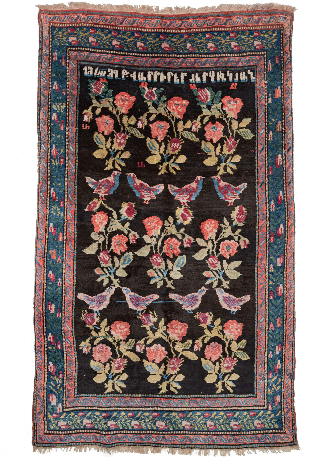 Antique Caucasian Armenian Karabagh area rug featuring a design of partridges and cabbage roses floating above a deep black field.  An inscription featuring a name and date in Armenian at the top:  